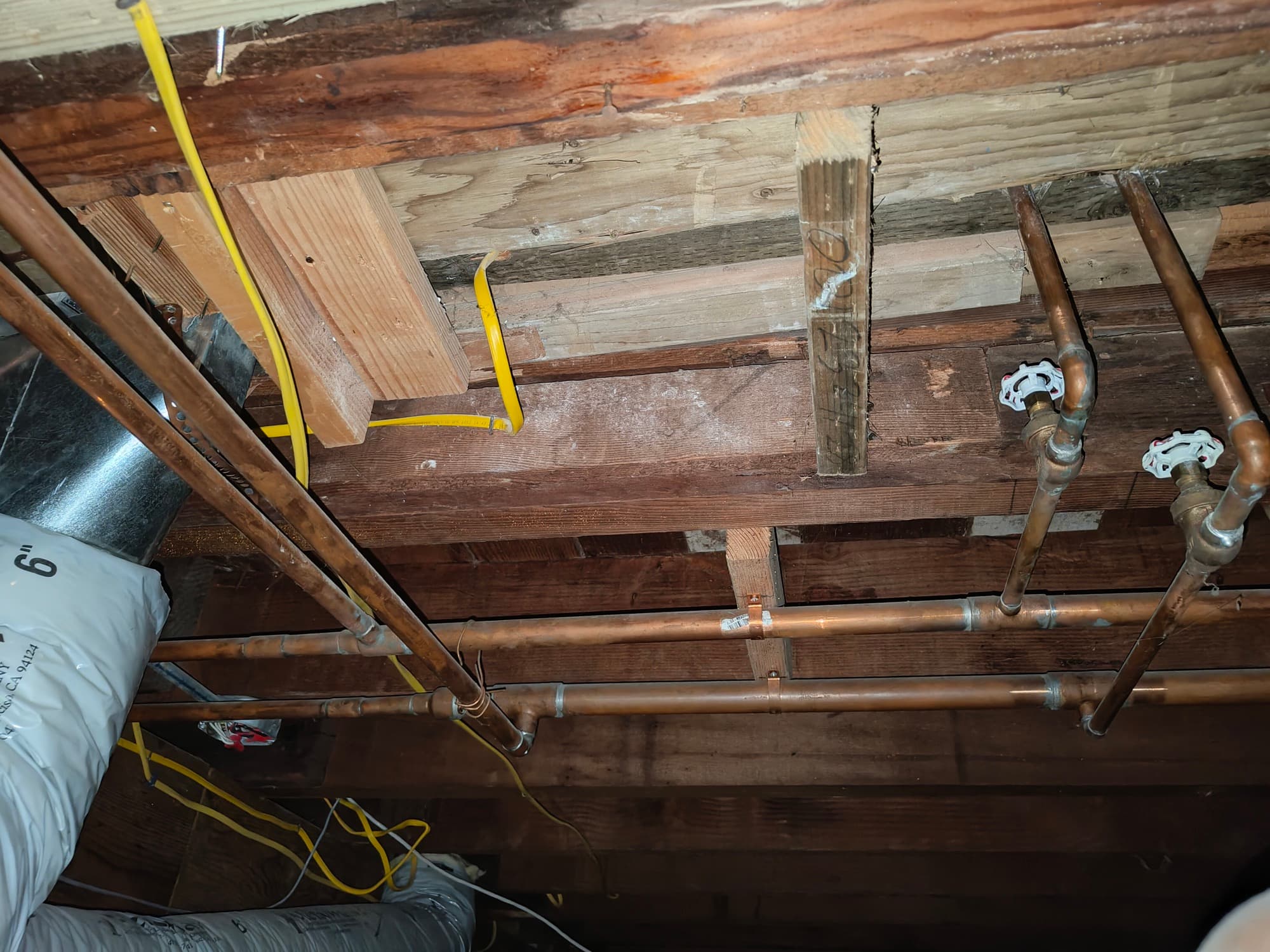 Under-floor joists and copper plumbing where power was routed